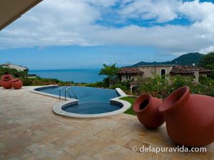 View of an infinity pool and the Pacific Ocean from the patio of a hillside house in Costa Rica.